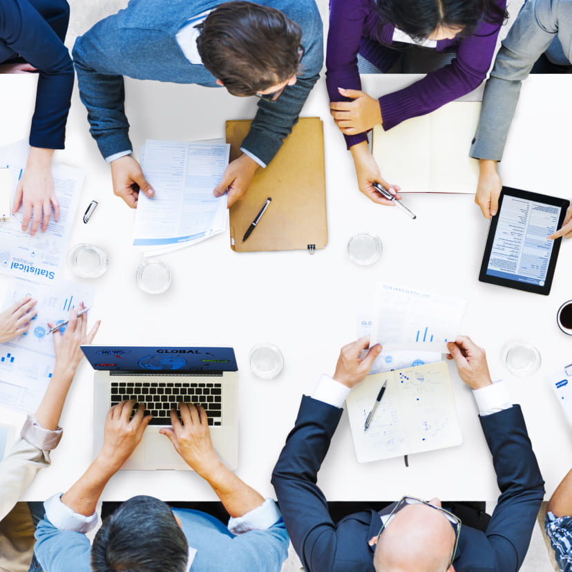 Office workers using computers, tablets, and charts.